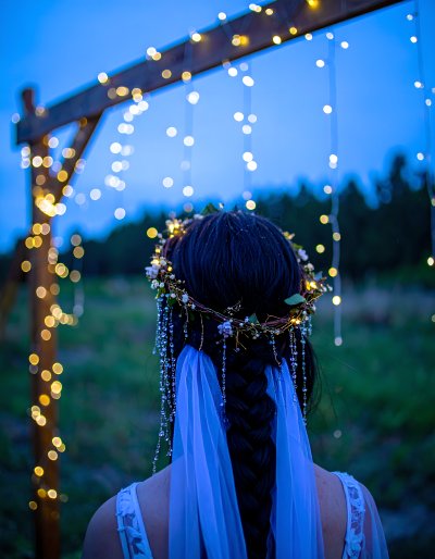 Woman with floral crown, veil, & fairy lights at twilight