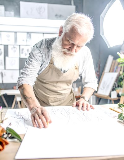 Elderly artist sketching in his studio with soft light