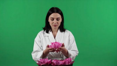 Woman with lotus flowers in white gi on green screen for wellness