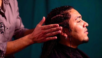 Hands styling intricate braids on man's head, hair transformation