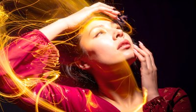 Woman's face in golden light trails, evoking wonder and creativity