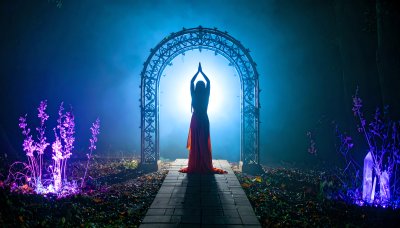 Woman meditating under magical archway in glowing forest