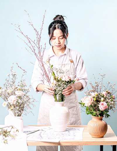 Woman skillfully arranging pink roses and baby's breath bouquet