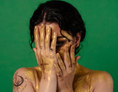 Enigmatic woman with gold paint on green screen for compositing projec