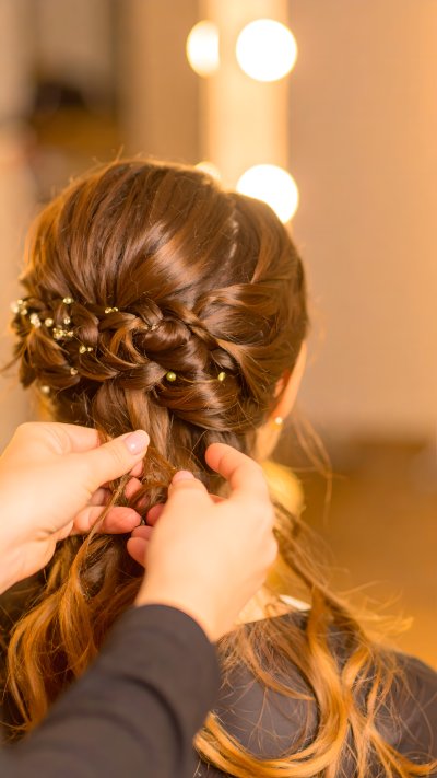 Hairdresser crafting elegant braided updo with pearls and gems