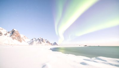 Magical Aurora over snowy mountains and calm sea