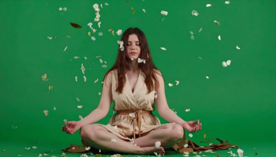 Meditating woman with falling petals on green screen for compositing