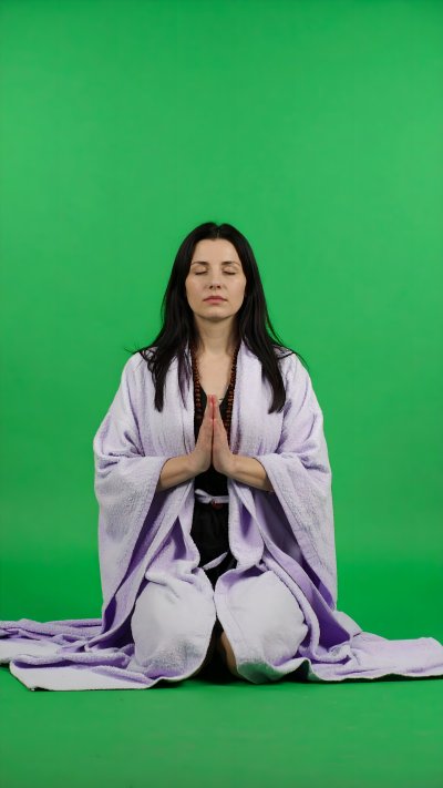 Woman meditating in lilac robe on green screen for wellness content