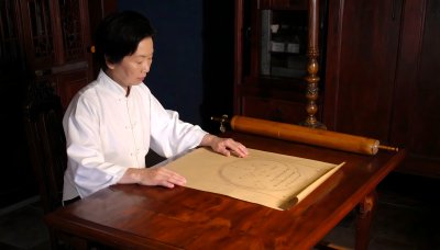 Woman in Chinese clothing studies ancient map scroll