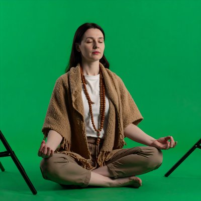 Woman meditating in lotus pose on green screen for compositing