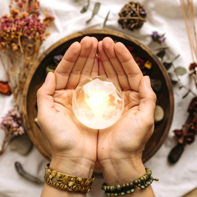 Hands hold glowing crystal, mystic elements, spiritual discovery