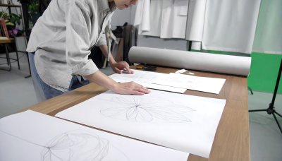 Artist sketching a blooming flower with focus in bright studio