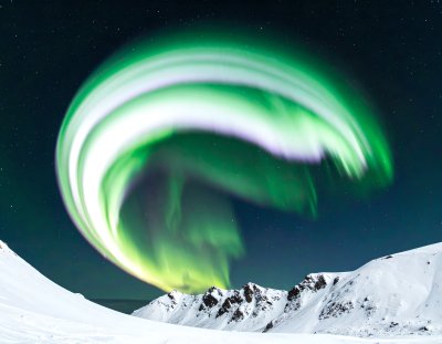 Aurora Borealis over snow-covered mountains at night with stars