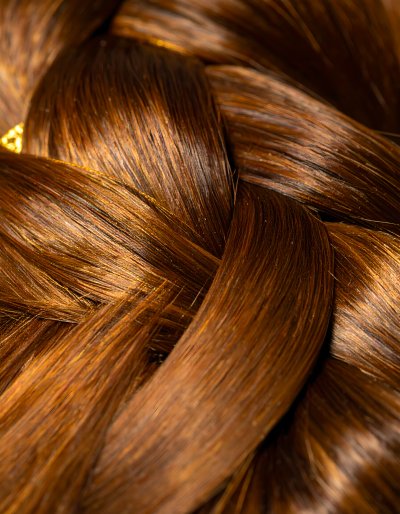 Intricate auburn hair braid illuminated by warm golden light