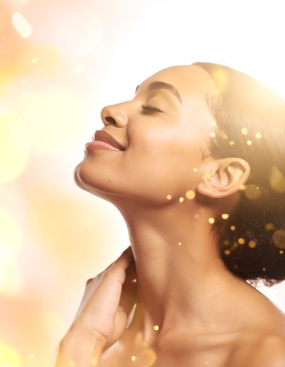 Woman with eyes closed, smiling in golden light with bokeh