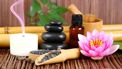 Serene spa scene with pink lotus, black stones, bamboo, candle, oil