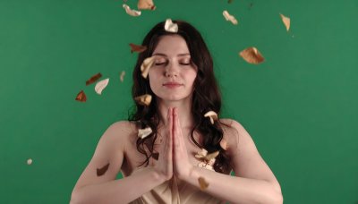 Woman in prayer with falling leaves on green screen