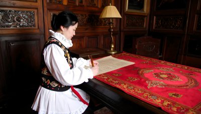 Woman in vintage dress writing in ornate study