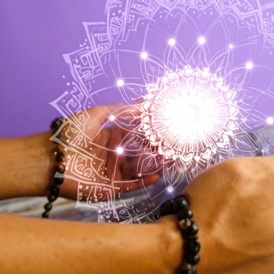 Praying hands in radiant mandala light.