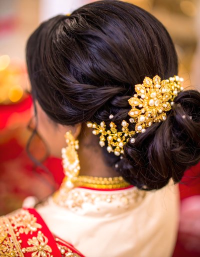 Elegant Indian bride with intricate hairstyle and gold pearl accessory