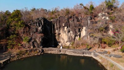 Tranquil lake reflects waterfall and figure, inviting serenity
