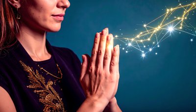 Woman praying, hands clasped, illuminated by glowing cosmic light web